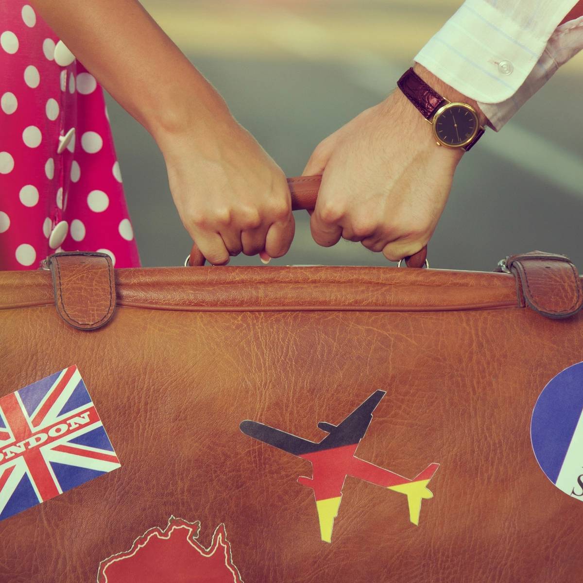 couple holding a suitcase with stickers from their amazing practical travel getaway